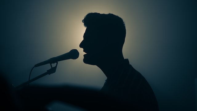 silhouette of man playing piano and singing into the microphone